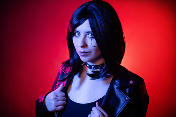 Portrait of young woman with bob haircut in black leather jacket illuminated with blue light posing...