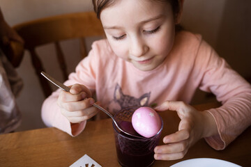 child paints eggs for easter at home.