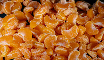 Peeled tangerines on a black background. Slices of tangerine or mandarin fruit close up