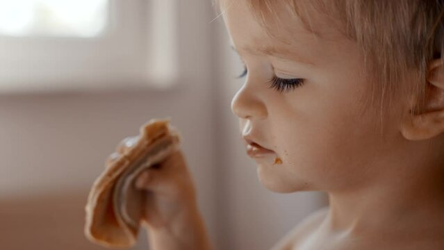 A video of a young child eating a piece of food, showcasing their actions and expressions during the meal.