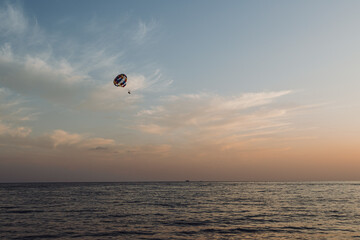 Parasailing.An active type of recreation at sea. A parachute floats in the sky. Vacationers rise above the water on a water parachute