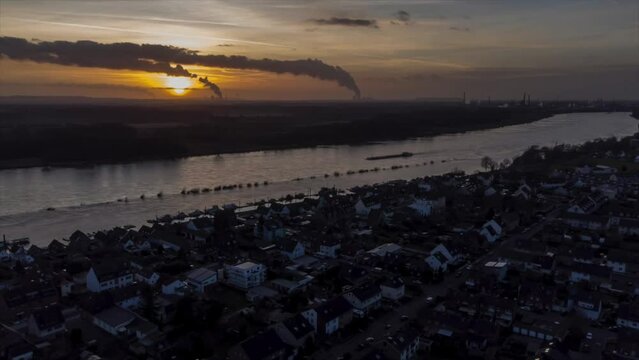 Zeitraffer Sonnenuntergang am Rhein aufgenommen mit einer Drohne aus der Luft, mit Schiffen und Industrie im Hintergrund.
