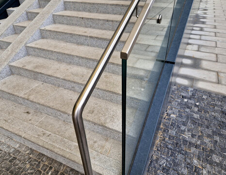 the edge of the glued glass of the railing covered by a U-shaped strip. transparent fillings of the railing made of shiny stainless steel tube bent. step into the building