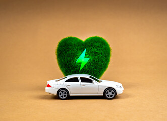 EV car, Electric energy battery charge vehicle with sustainable development concept. White car parked at green heart-shape with electric power icon, alternative energy, brown kraft paper background.