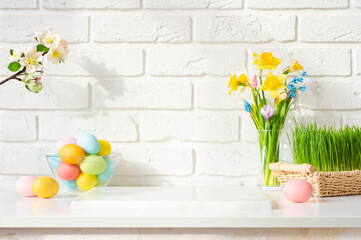 Stone podium on table decorated with easter eggs and spring flowers on white brick wall background