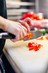 Obraz na płótnie Canvas Chefs woman hands chopping red pepper on board