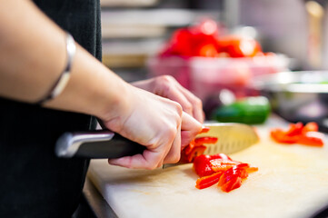 Chefs woman hands chopping red pepper on board