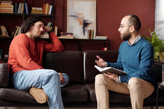 Middle Eastern psychotherapist sitting on couch in front of Caucasian patient with depression discussing treatment plan