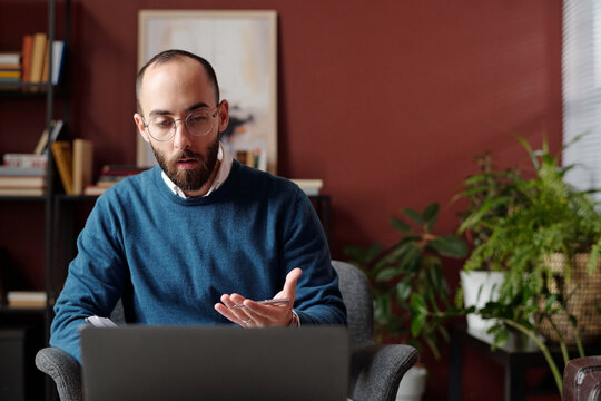Modern Middle Eastern psychologist sitting in front of laptop talking to patient through video call, copy space