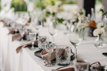 Serving, setting table in the backyard. Plate and glass, stack, wineglass, luxury rich decor. Wedding set up, dinner table reception on terrace. Birthday, baptism, event. Closeup details of interior.