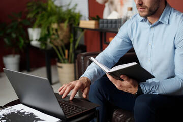 Professional psychologist holding notebook preparing for therapy session using laptop