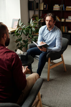 Vertical high angle view of Caucasian doctor working with depressed man, conducting psychotherapy session