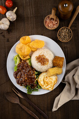 Nasi pecel an Indonesian food made with boiled mix green leaf vegetable with peanut sauce, fried egg, fried tofu, tempeh and crackers.
