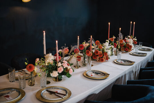 Birthday celebration in restaurant. Wedding set up, reception closeup. Festive dinner table decorated with flower and greenery, candles. Serving, setting table. Plate, silverware cutlery, glasses.