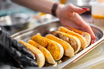 Chef hand cooking set hot dog on kitchen