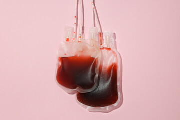 Bags with donor blood on pink background, top view