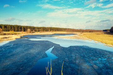 Aerial view of countryside and frozen stream on a sunny spring day. Beautiful natural landscape