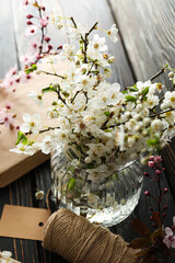 Spring twigs with flowers in a jar, on a dark wooden background.