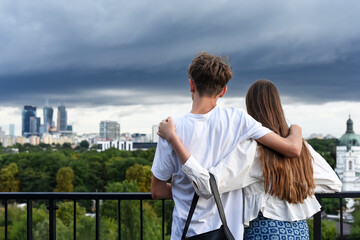 a guy and a girl, hugging each other, stand on the roof of a building, admiring the beautiful view...