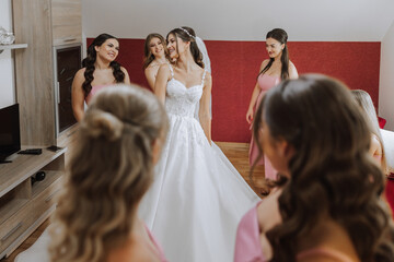 Wedding morning. Bridesmaids help put on the white wedding dress. A young woman is preparing to...