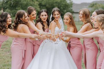 Photo bride with her friends drinking champagne from glasses. Cropped shot of a beautiful young bride and her bridesmaids having champagne before the wedding.