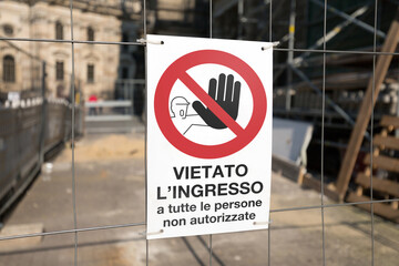 Cartello vietato l'ingresso posto su una rete metallica all'inizio di un cantiere. Sfondo sfocato,...