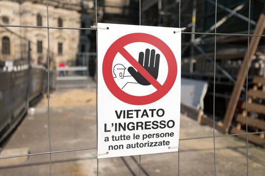 Cartello vietato l'ingresso posto su una rete metallica all'inizio di un cantiere. Sfondo sfocato, focus sul segnale in primo piano.