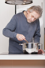 Older man in kitchen boiling spaghetti for classic receipe