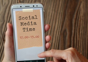 Woman hands search online news from smartphone, with with text written note SOCIAL MEDIA TIME...