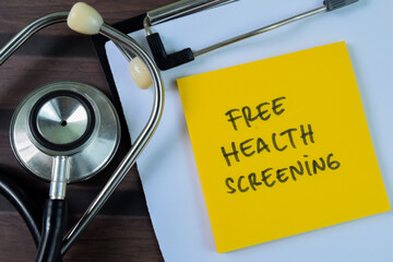 Concept of Free Health Screening write on sticky notes isolated on Wooden Table.