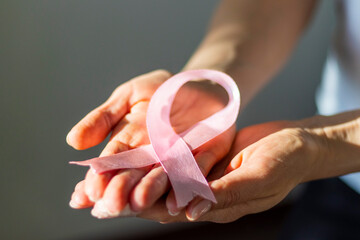 Shot of a woman holding pink ribbon, symbol of a breast cancer awareness. Concept