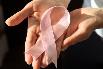 Shot of a woman holding pink ribbon, symbol of a breast cancer awareness. Concept