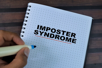 Concept of Imposter Syndrome write on book isolated on Wooden Table.