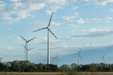 Panoramic view of wind farm or wind park, with high wind turbines for generation electricity with...