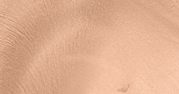 Delicate gold shimmer in peach fuzz paint color. Golden particles slowly move in nude ink. Smooth motion of watercolor palette. Gentle shiny texture of flowing background. Copy space. Tender backdrop