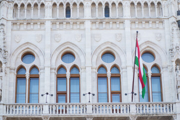 Naklejka premium Facade of the Hungarian Parliament with the flag of Hungary. Beautiful facade of the building.
