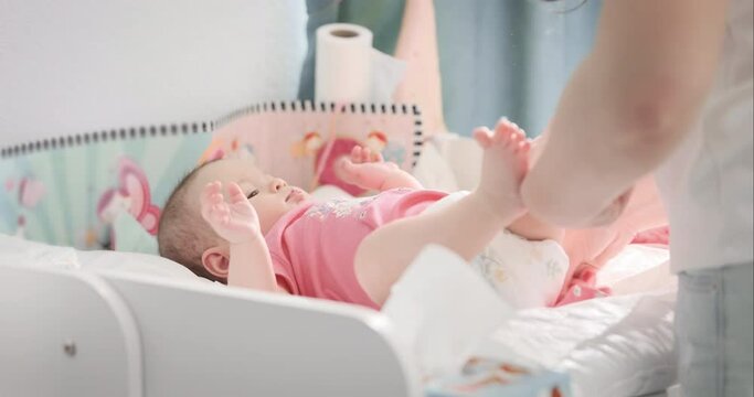 Mother check baby diaper on changing table at light home. Mom taking care, change nappy of adorable newborn infant indoor. Hygiene of cute little child. Parent love, commitment. Patience parenthood