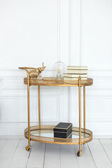 Golden decorative serving table trolley with cozy decor in interior living room. Cozy light...