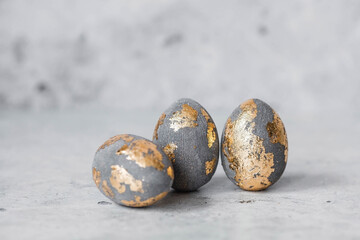 Stylish beautiful grey Easter eggs with golden potali coating on a grey background. The concept of happy Easter 2024.
