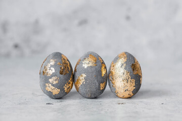 Stylish beautiful grey Easter eggs with golden potali coating on a grey background. The concept of...