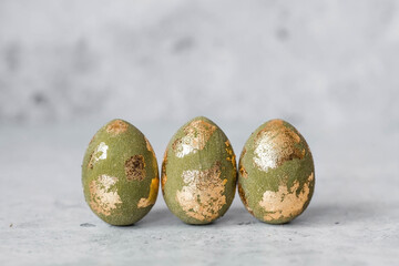 Stylish olive-colored Easter eggs with a coating of golden sweat on a gray background. The concept...