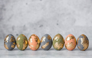 Stylish beautiful Easter eggs with golden potali coating on a gray background. The concept of happy...