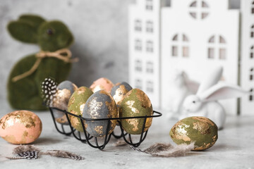Stylish beautiful Easter eggs with golden potali coating and Easter bunny on a gray background. The...
