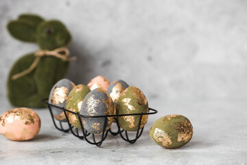 Stylish beautiful Easter eggs with golden potali coating and Easter bunny on a gray background. The...