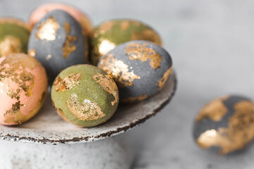 Beautiful Easter eggs with a golden coating were laid on a steel concrete plate on a gray...