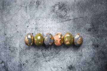 Stylish beautiful Easter eggs with golden potali coating on a gray background. The concept of happy...