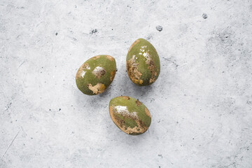 Stylish olive-colored Easter eggs with a coating of golden sweat on a gray background. The concept...