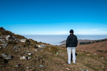 Explorador no pico da montanha de La Rhune: Turista a contemplar o mar de nevoeiro nas alturas