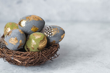 Stylish beautiful Easter eggs with a golden coating of sweat and feathers in a bird's nest of...