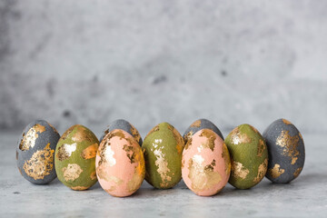 Stylish beautiful Easter eggs with golden potali coating on a gray background. The concept of happy Easter 2024.